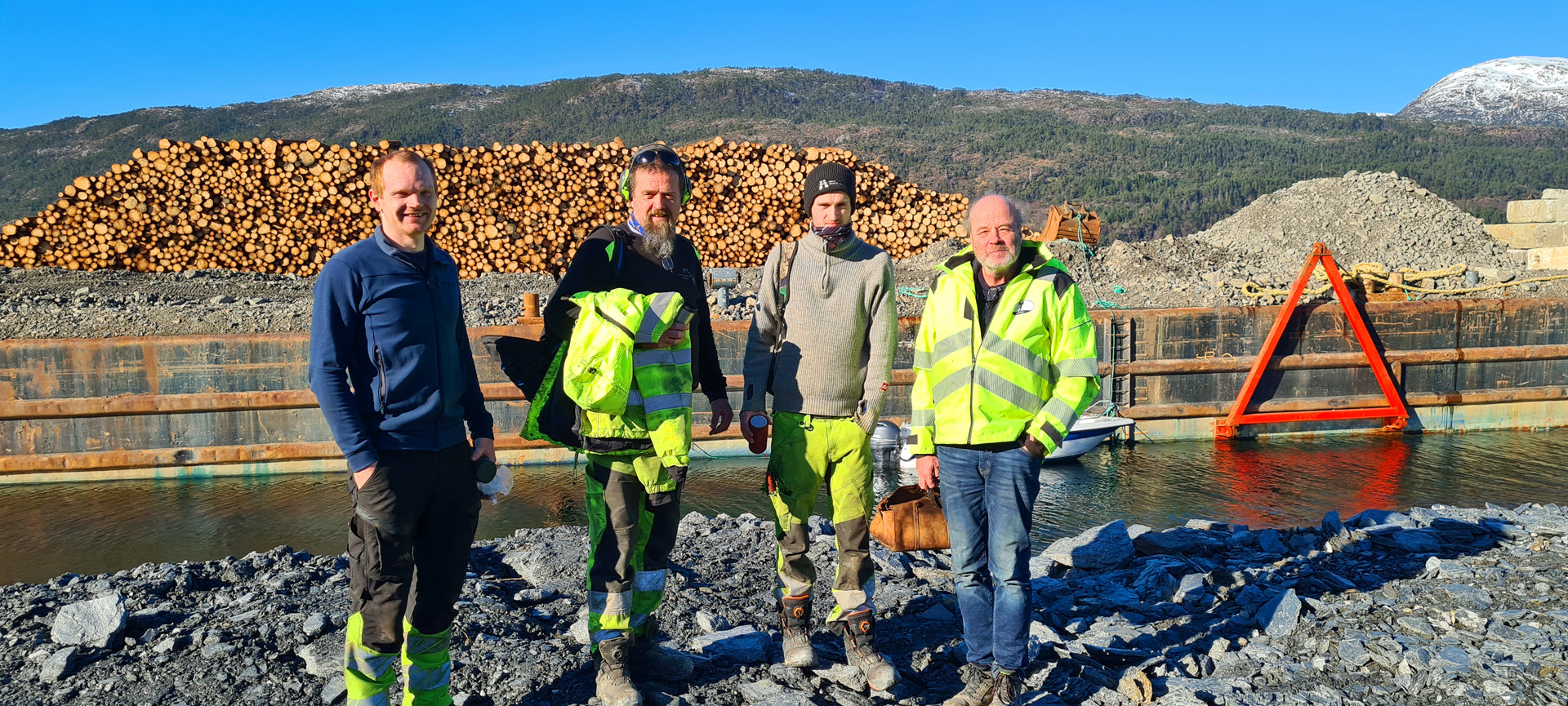 20230301_115352 Full fart på Samnøy om dagen. F.v. skogsentreprenør Terje Austestad, Arne og Steffen Kvamsdal i Helldal AS og til høgre sjefen sjølv i entrepernørfirmaet Helldal AS Jim Heldal.
Legg merke til lekteren med tømmeret i bakgrunnen. Jim Heldal har mykje erfaring med kaibygging, og seier at bruk av lekteren har gitt ei rasjonell totalløysing i dette tilfellet.
Foto: Helge Kårstad
